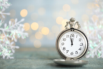 Pocket watch and festive decor on table against blurred lights, space for text. New Year countdown