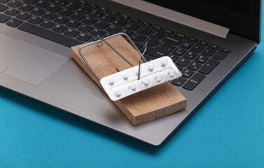 Mousetrap with blister of pills on laptop keyboard. Health and business concept.