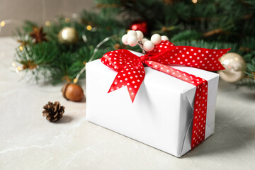Fototapeta na wymiar Christmas gift box with red bow and festive decor on light table