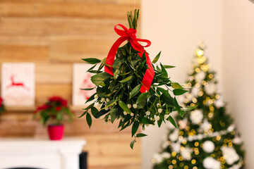 Mistletoe bunch with red bow hanging in room decorated for Christmas