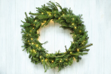 Beautiful Christmas wreath with festive lights on white wooden background, top view © New Africa
