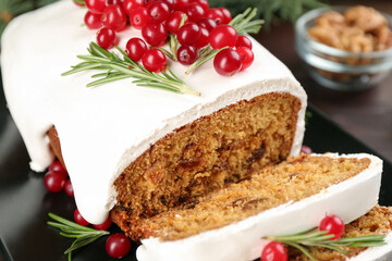 Fototapeta na wymiar Traditional classic Christmas cake decorated with cranberries and rosemary on black plate, closeup