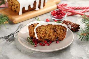 Traditional classic Christmas cake decorated with cranberries, pomegranate seeds and rosemary on light table