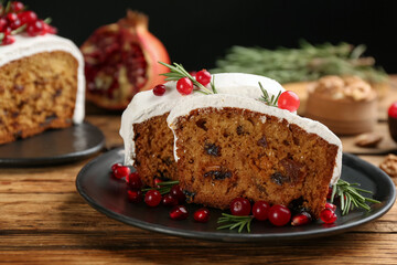 Traditional classic Christmas cake decorated with cranberries, pomegranate seeds and rosemary on wooden table