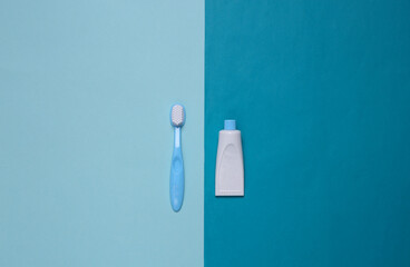 Toy toothbrush and a tube of toothpaste on a blue background. Top view. Minimalism