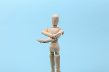 Wooden puppet stretches arms isolated on blue background. Healthy lifestyle, sport concept