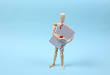 Wooden puppet holding ace of hearts on blue background.