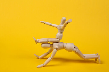 Fatherhood. Spending time with children. Two puppet personified father and son are spending time together playing and fooling around on yellow background