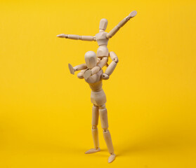 Fatherhood. Spending time with children. Two puppet personified father and son are spending time together playing and fooling around on yellow background