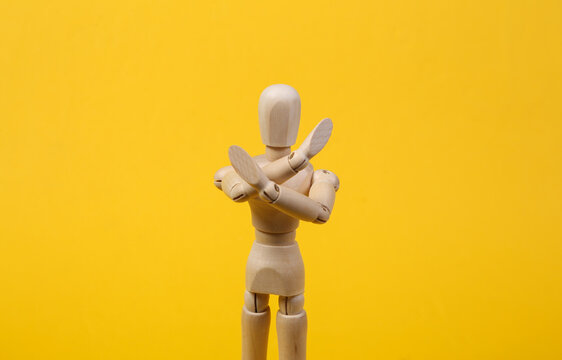 Wooden puppet crossed arms showing stop sign on yellow background