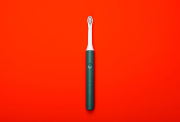 Modern electric toothbrush on red background. Top view. Teeth care. Minimalism