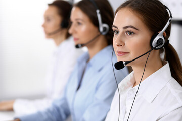Call center. Group of operators at work. Fo us on beautiful business woman in headset