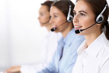Call center. Group of operators at work. Fo us on beautiful business woman in headset