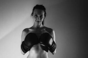Nude beautiful girl with a boxing gloves. Black and white photo