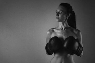 Nude beautiful girl with a boxing gloves. Black and white photo