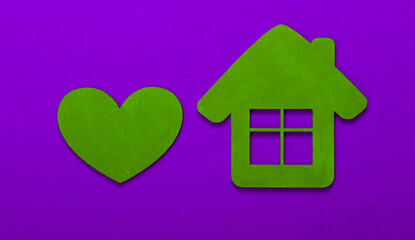 House figurine and heart on purple background. Top view