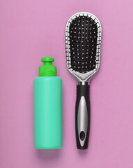 Hair brush with shampoo bottle on pink pastel background. Hair care. Hygiene. Beauty flat lay. Top view
