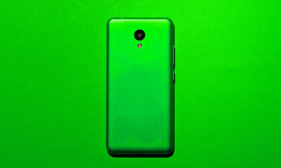 Green smartphone on green background. Top view