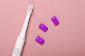 Electric Toothbrush with chewing gum on pink background. Caring for dental health, fresh breath