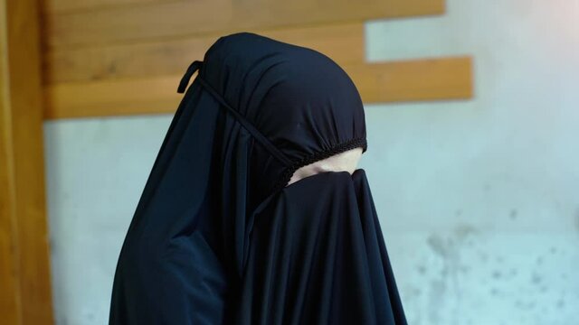 Portrait of an Asian muslim women in a daily prayer at home reciting Surah al-Fatiha passage of the Qur'an in a single act of Sujud called a Sajdah or prostration