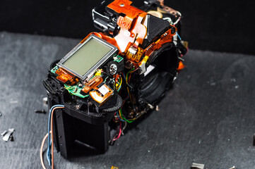 Professional repair of photographic equipment. Disassembled SLR camera on stone table on dark...