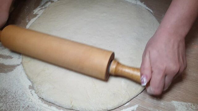 a woman rolls out the dough with a rolling pin for making homemade cakes, home video on the phone