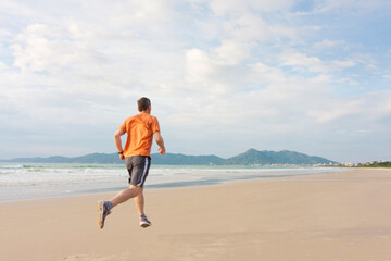 Fototapeta na wymiar Mature man running on a long beach early in the morning
