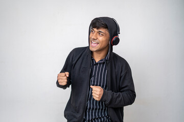 young handsome man listening music with headphones wearing a black hoodie smiling face standing on white background