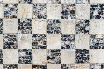 Graffiti carved on a wall. Love declarations. Stone wall of flint and limestone carved many graffiti. Chapelle des Marins in Saint-Valery-sur-Somme, France