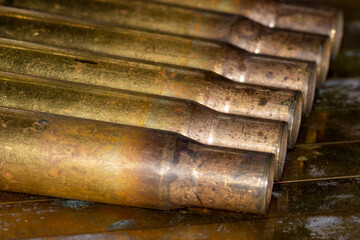 Close up of multiple 50 caliber BMG copper empty shell casings on grunge background