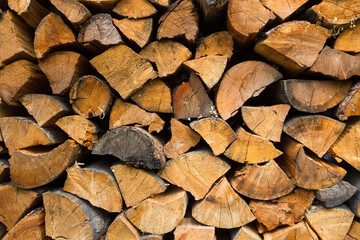 Background of dry chopped firewood logs stacked up on top of each other