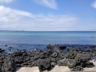 Fototapeta na wymiar Jeju Island, beach, sea, cloud, black stone, rock, blue sky, Sunshine, tree, peace, horizon, emerald color, Korea