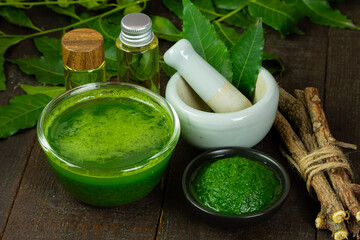 Neem leaf used as ayurvedic medicine with neem oil and stick on wooden background.