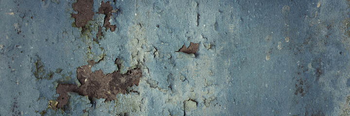 Peeling paint on the wall. Panorama of a concrete wall with old cracked flaking paint. Weathered rough painted surface with patterns of cracks and peeling. Wide panoramic grunge texture for background