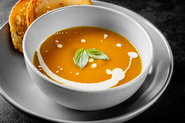 Pumpkin soup in bowl on Dark grey black slate background