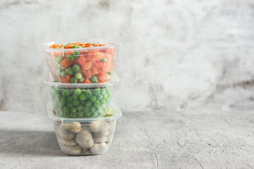 Plastic containers and bags with different frozen vegetables.