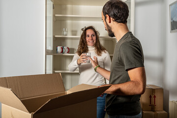 Happy couple with moving boxes in a move house wiht a jarr in team mate