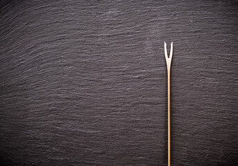 Fondue fork on the dark background with copy space. Flat lay, top view