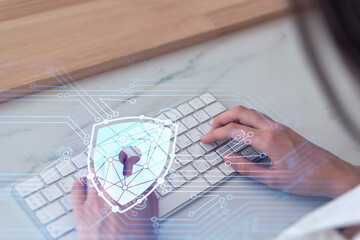 A woman programmer is typing a code on computer to protect a cyber security from hacker attacks and save clients confidential data. Padlock Hologram icons over the typing hands. Formal wear.