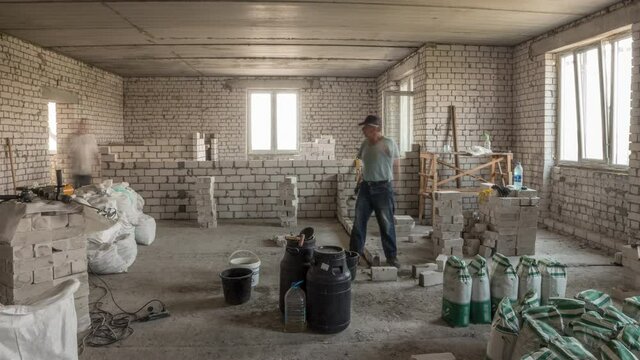 Builders laying brick walls inside appartment with professional tools timelapse. Workmen at work, bricklayers building wall, contractor and worker. Building materials around