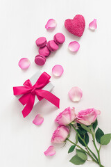 Fototapeta na wymiar Valentine's Day. Festive breakfast. Roses, gift box, macaroon and heart decorated with rose petals. White painted old wooden background. Top view, flat lay.