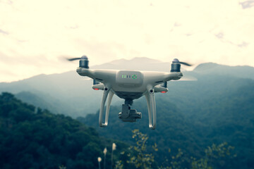 White drone with camera flying in spring mountains