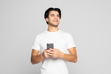 Daylight portrait of young man use phone isolated on gray background wearing white t-shirt standing in front of camera