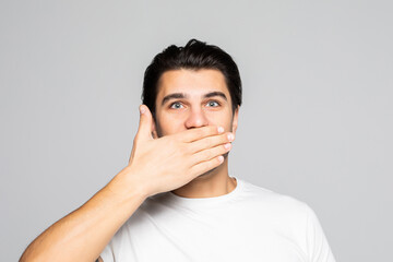 Portrait of amazed man covering his mouth isolated over white background