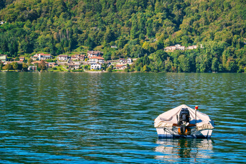 Leisure boat, moored in the Orta Lake (piedmont, Northern Italy) seen from the city of Orta, along the lake shores during early fall season. UNESCO World Heritage Site,.