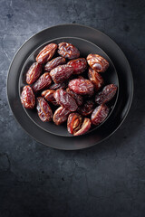 Dried sweet dates on a black plate.