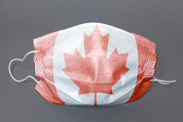 Medical protective mask with Flag of Canada on grey background