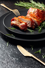 Grilled pork ribs on a black plate.
