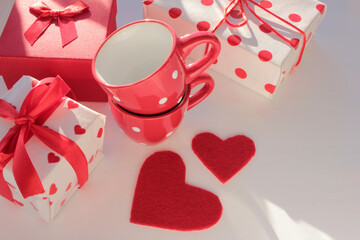 Gift box with red ribbon, felt heart, and espresso coffee cup on white table. Top view, copy space. Valentines day concept