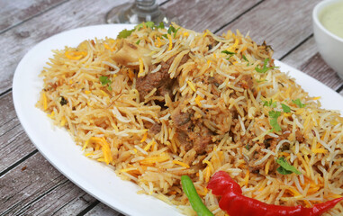 chicken biryani with pickle and yoghurt garnished with spices stone background 